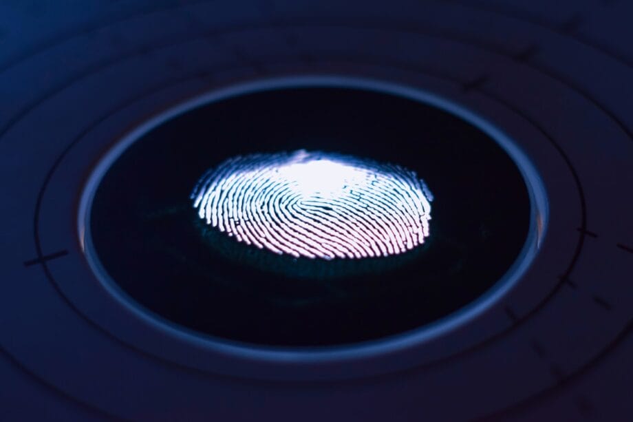 A close-up of a fingerprint illuminated on a circular scanner surface, showing ridge details and surrounding circular markings.
