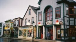 A row of colorful small shops and a breakfast restaurant on a quiet, wet street in a quaint town.