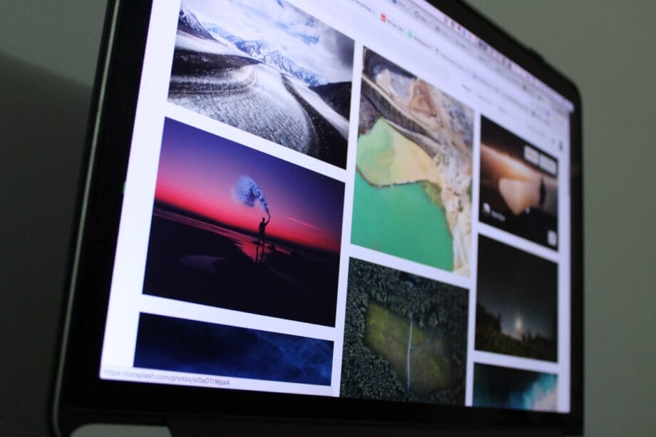 A computer monitor displays a grid of various landscape and nature photographs on a website.