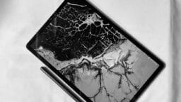 A tablet with a cracked screen and stylus on a white surface, displaying the time 4:29.