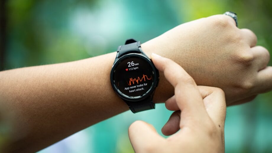 A person checks a smartwatch displaying a heart rate of 172 bpm and a warning about a possible heart attack.