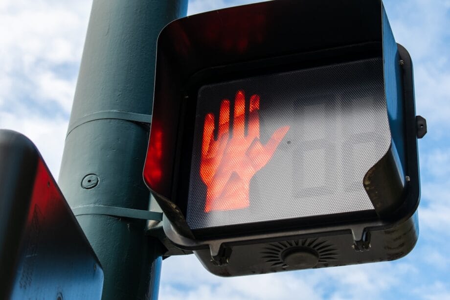 Close-up of a pedestrian signal showing a red hand, indicating that it is not safe to cross the street.