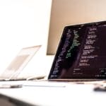 black laptop computer turned-on displaying source code on table