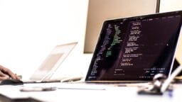 black laptop computer turned-on displaying source code on table