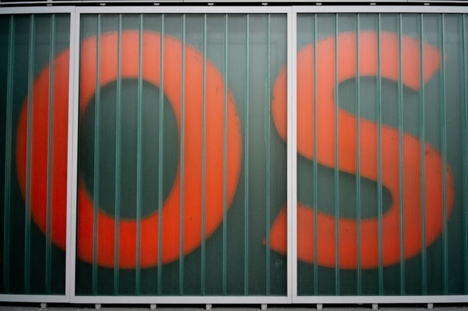 Large red letters O and S are partially visible behind a paneled glass wall with vertical metal bars.