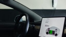 Interior of a car showing a dashboard screen with an electric vehicle charging status, indicating 55 minutes left and 202 km range.