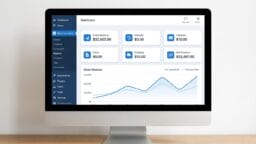 A computer monitor displays a WooCommerce dashboard with sales statistics and a line graph of gross revenue trends.