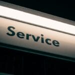 A close-up view of a metallic sign with the word Service printed in black capital letters.