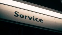 A close-up view of a metallic sign with the word Service printed in black capital letters.
