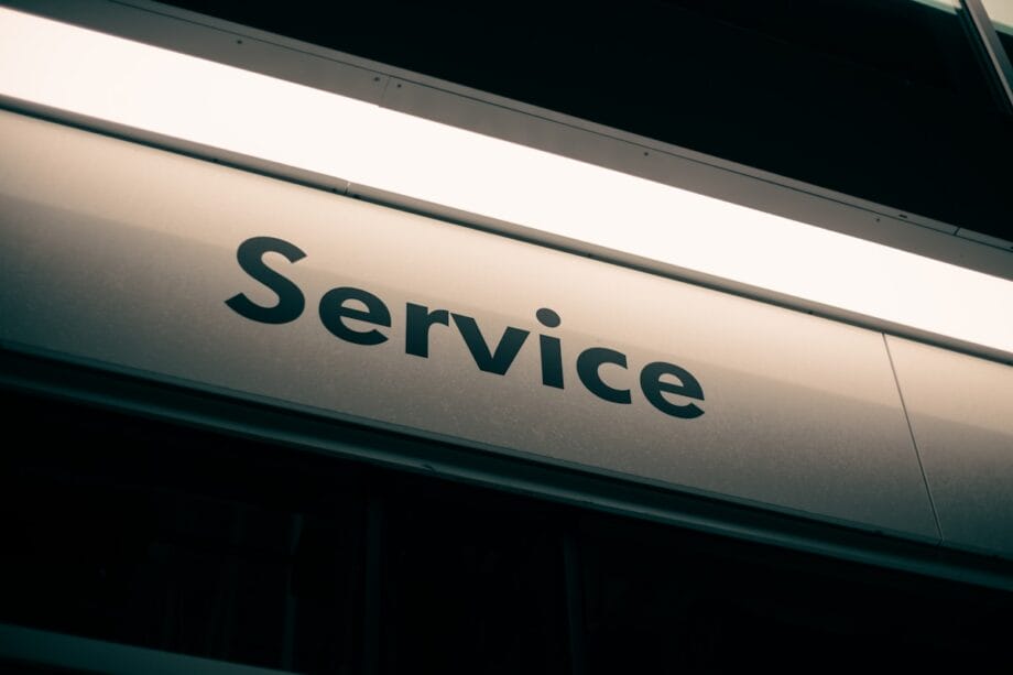 A close-up view of a metallic sign with the word Service printed in black capital letters.