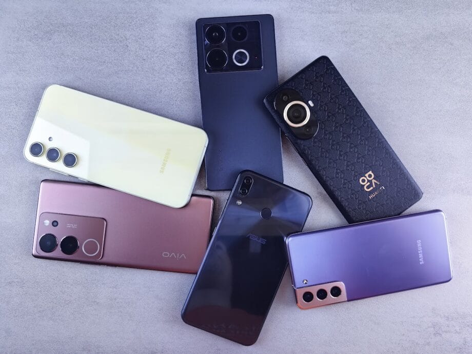 Six different smartphones from various brands are arranged on a flat, light gray surface.