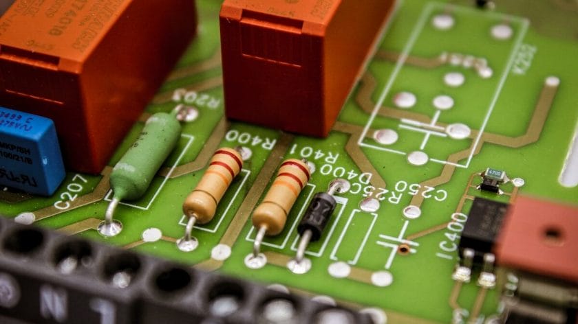 Close-up of an electronic circuit board showing resistors, a diode, capacitors, and visible circuit traces.