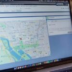 A MacBook Pro displays a map of Washington, D.C. on its screen, with a webpage and a red location pinpoint visible.