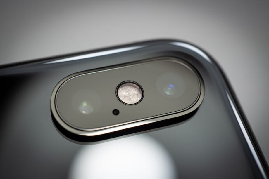 Close-up of a smartphone’s dual rear cameras and flash on a glossy black surface.