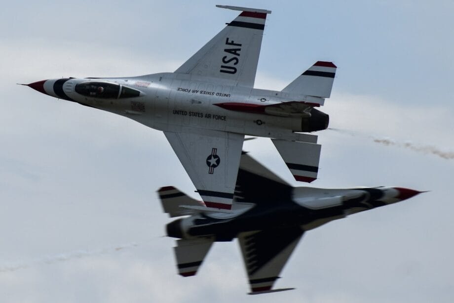 A fighter jet flying through a cloudy blue sky
