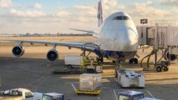 A large commercial airplane parked at an airport gate with ground service vehicles nearby.