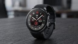 A black smart watch displaying the time, date, heart rate, and various fitness tracking features rests on a table.