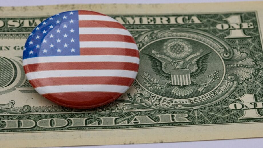 A button with the American flag design placed on top of a U.S. one dollar bill.