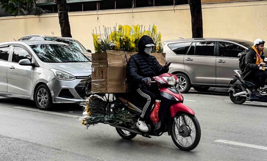 Person riding a motorcycle loaded with flowers.