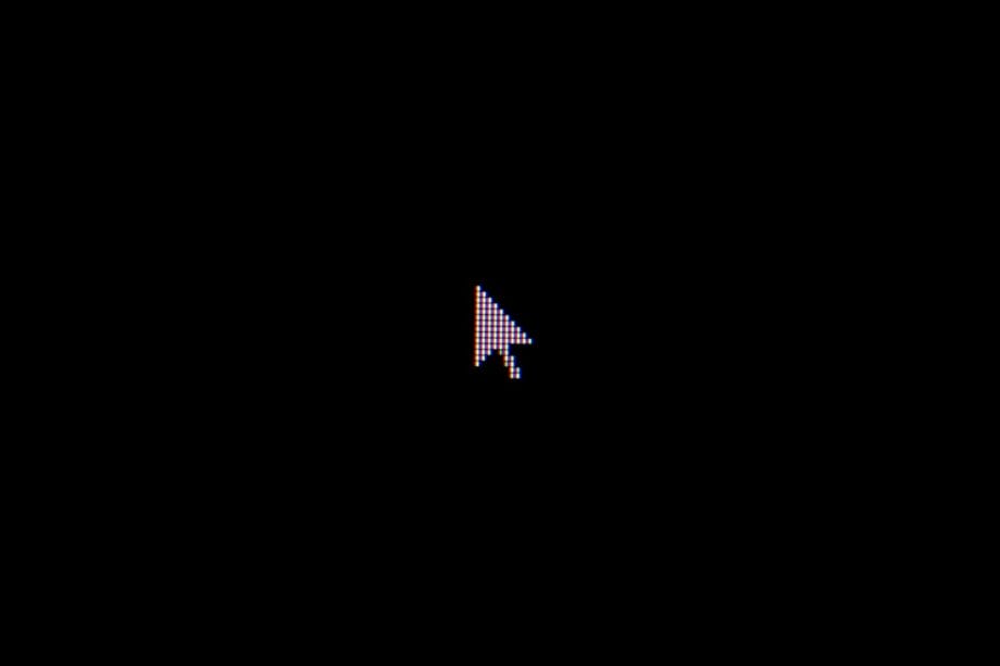 A pixelated computer mouse pointer cursor is centered on a black background.