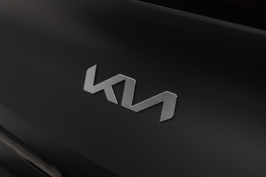 Close-up of a silver Kia logo on a matte black car surface.