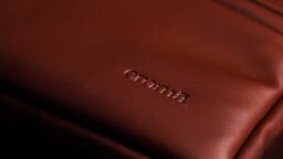 Close-up of a brown leather bag with the brand name croma embossed on the surface.