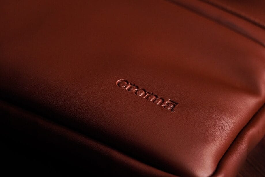Close-up of a brown leather bag with the brand name croma embossed on the surface.