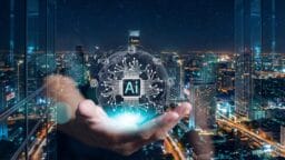 A hand holds a digital globe with an AI chip graphic, against a city skyline at night with illuminated buildings.