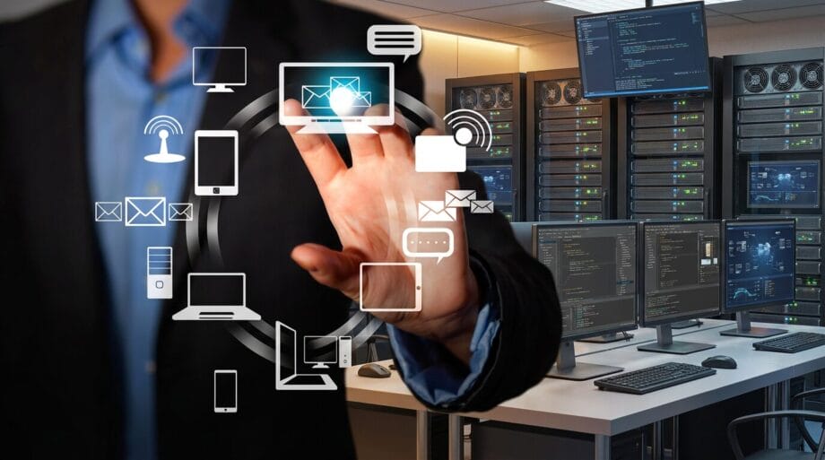 A person interacts with digital communication icons on a transparent screen, with computer servers and monitors in the background.
