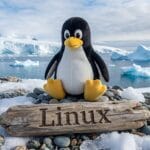 A penguin plush toy sits on rocks near a wooden sign reading Linux, with icebergs and snowy landscape in the background.