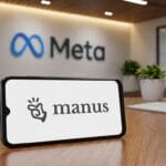 A smartphone on a desk displays the Manus logo, with a Meta sign in the background of a modern office setting.