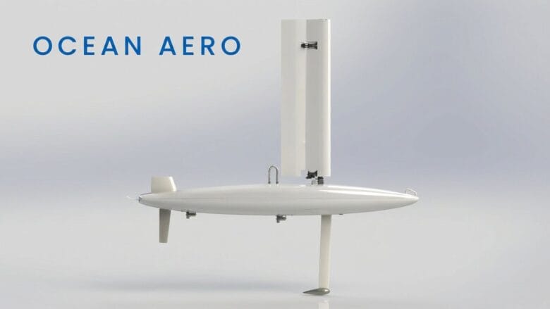 A white autonomous sail-powered marine drone with a vertical sail and rudder, labeled Ocean Aero on a plain background.
