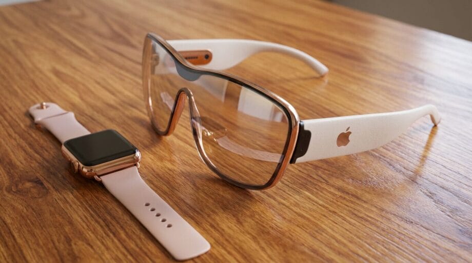 A smart watch and a pair of augmented reality glasses with white and gold accents are placed on a wooden surface.