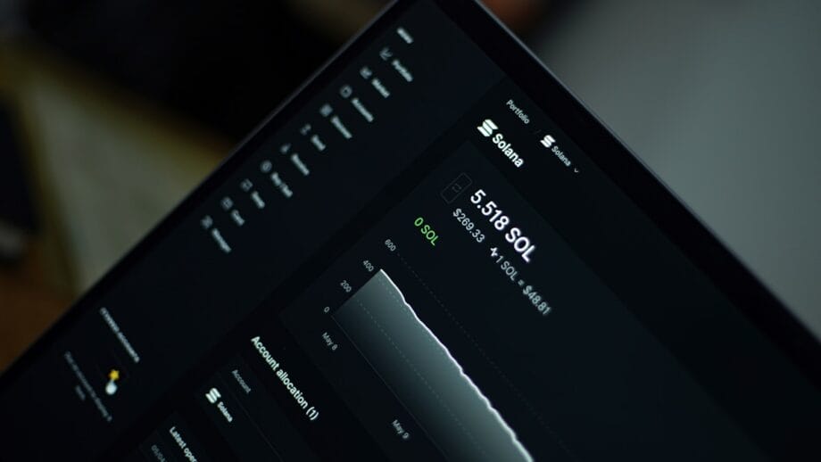 A laptop screen displays a dashboard with Solana SOL cryptocurrency balance, price chart, and account information.