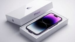 A new iPhone with a gradient screen is displayed inside an open white Apple box on a light background.