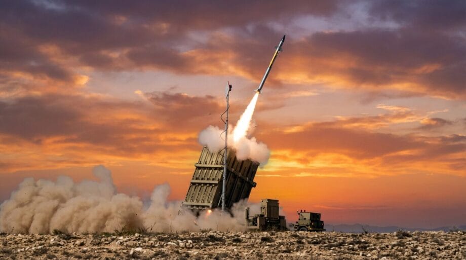 A missile is launched from a ground-based defense system at sunset, with smoke and clouds in the background.