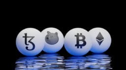 Four white spheres with cryptocurrency logos—Tezos, Dogecoin, Bitcoin, and Ethereum—are reflected on a rippled surface against a black background.