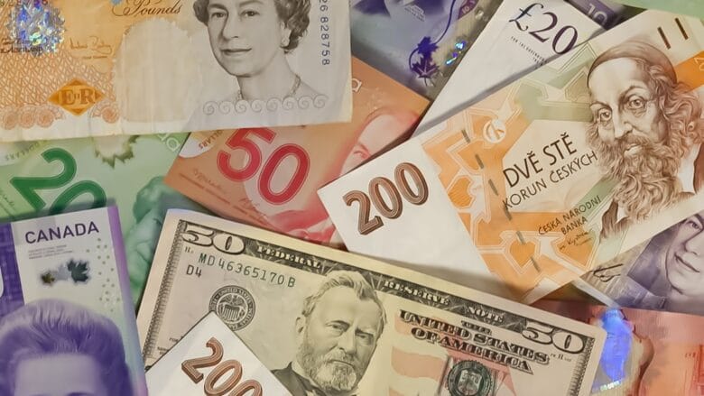 Various international banknotes, including Canadian dollars, US dollars, British pounds, Czech koruna, and euros, overlapping each other.
