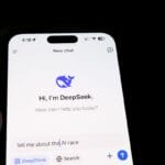 A smartphone screen displays an AI chatbot app called DeepSeek, with the prompt “Tell me about the AI race” entered.