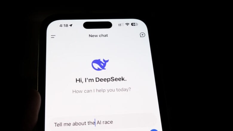 A smartphone screen displays an AI chatbot app called DeepSeek, with the prompt “Tell me about the AI race” entered.