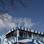 A building with blue and white geometric patterns and a rooftop sign that reads soho against a blue sky.