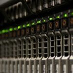 Close-up of server rack with multiple hard drive bays and indicator lights in a data center.