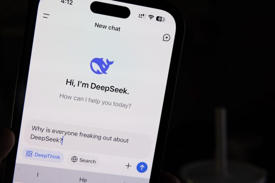 A smartphone screen displays a chat with DeepSeek, showing the message: &ldquo;Why is everyone freaking out about DeepSeek?&rdquo;.