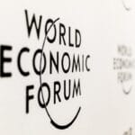 The World Economic Forum logo is displayed in black text on a white wall.