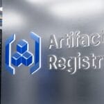 A metallic server rack labeled Artifact Registry with a blue logo, surrounded by other server racks and data center equipment.