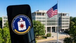 A smartphone displays the Central Intelligence Agency logo in front of the CIA headquarters building with a US flag outside.