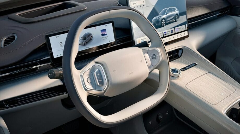 Modern car interior with a digital dashboard, touchscreen displays, light-colored steering wheel, and minimalist center console.