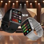 Two smartwatches, one black and one white, are displayed in front of a stage with Kore Di Launch on the backdrop.