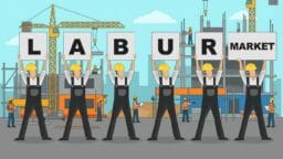 Five construction workers in hard hats hold signs spelling LABOUR MARKET at a building site with cranes and other workers in the background.