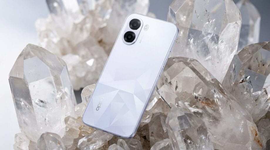 A white Oppo smartphone with dual cameras is placed upright among large clear quartz crystals.